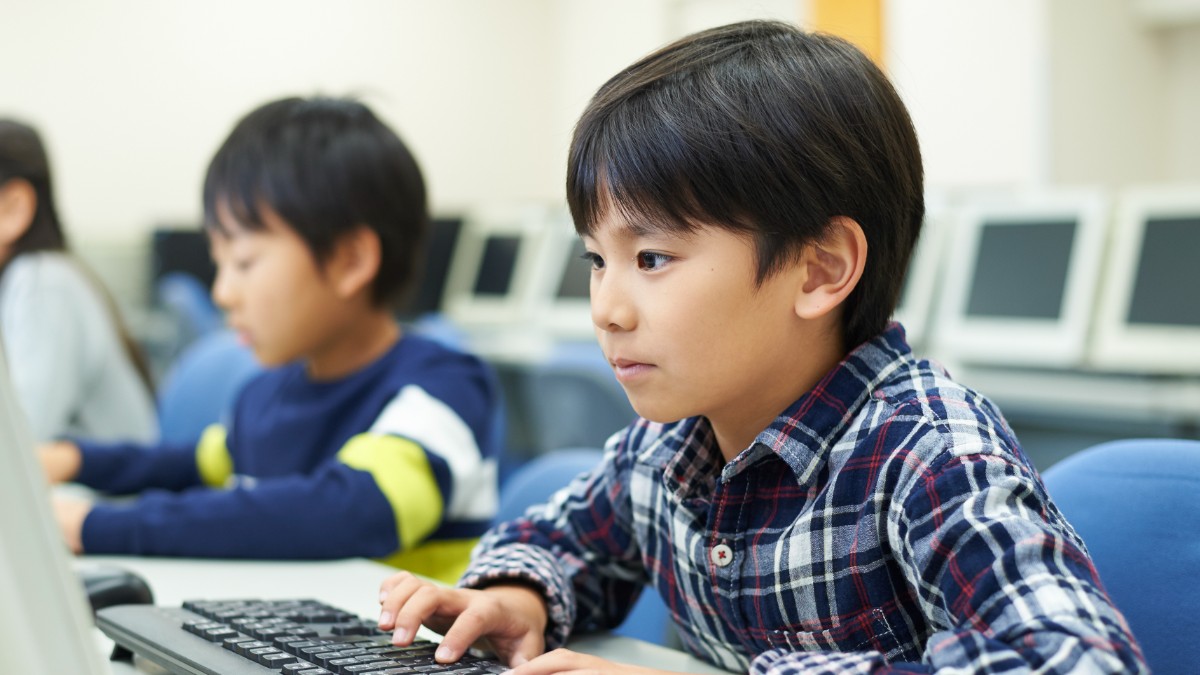 笑顔でプログラミングする小学生